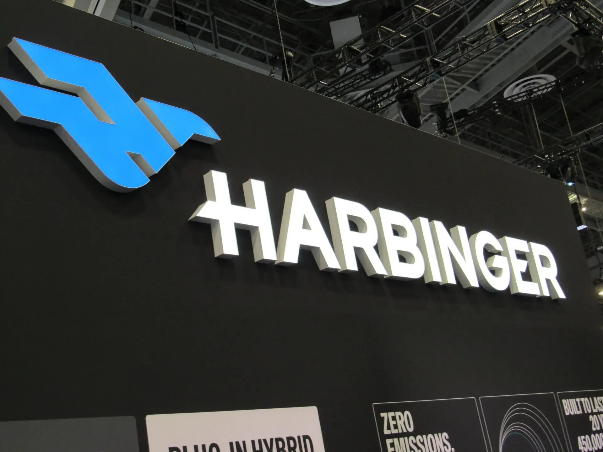 Illuminated Harbinger channel logo on a black architectural wall