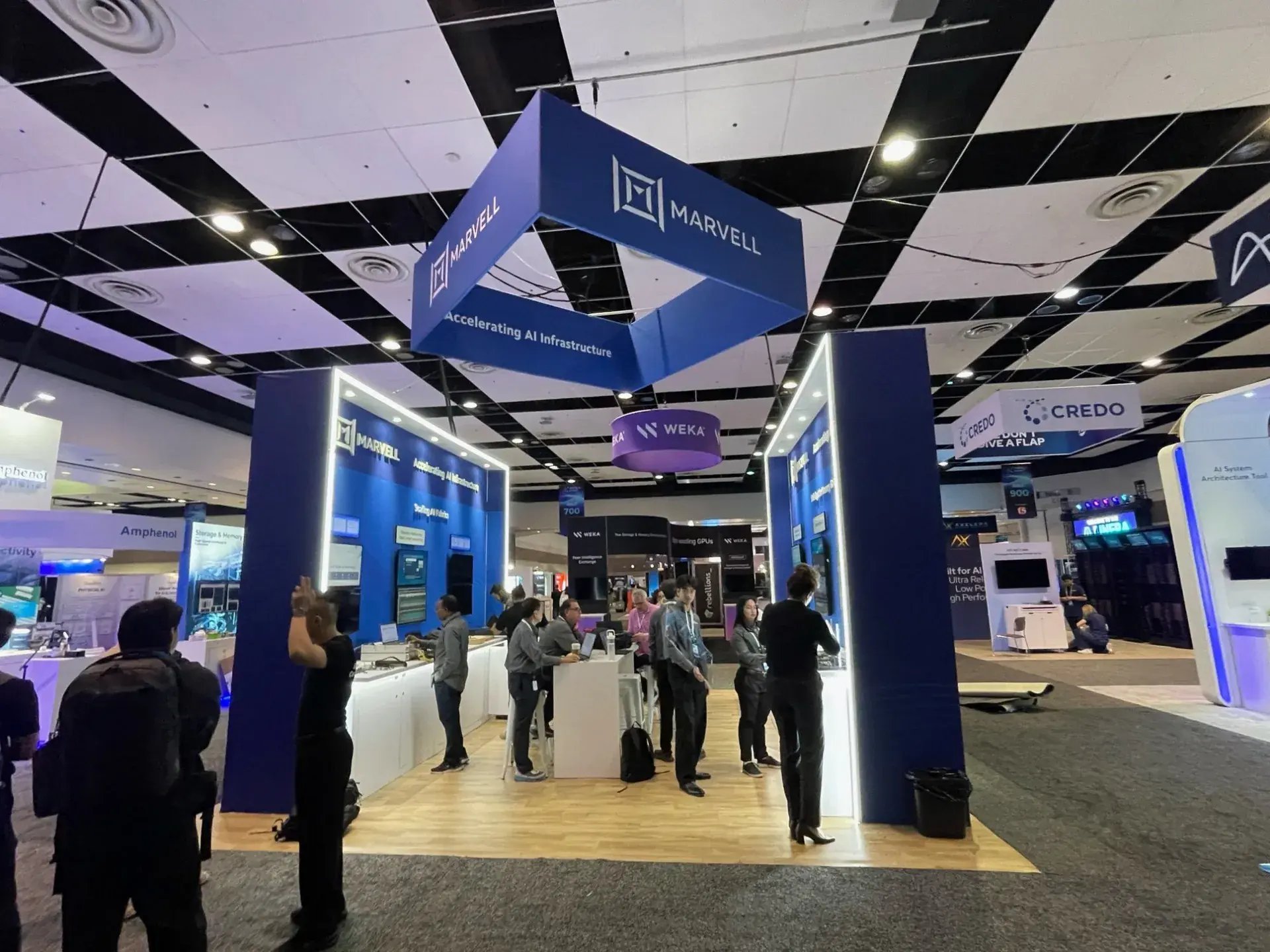 Marvell 20x20 island exhibit at AI Infra Summit with two demo walls, illuminated counters and a 12x12 hanging sign
