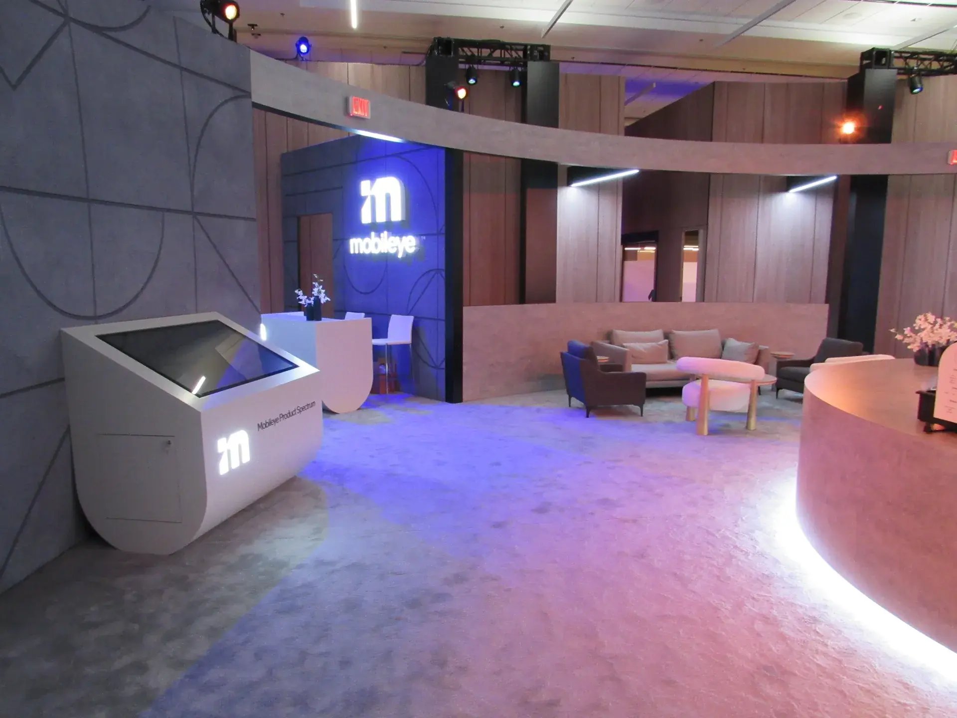 Convention center meeting room transformed into a branded experiential environment with curved architectural walls, illuminated logo and lounge seating
