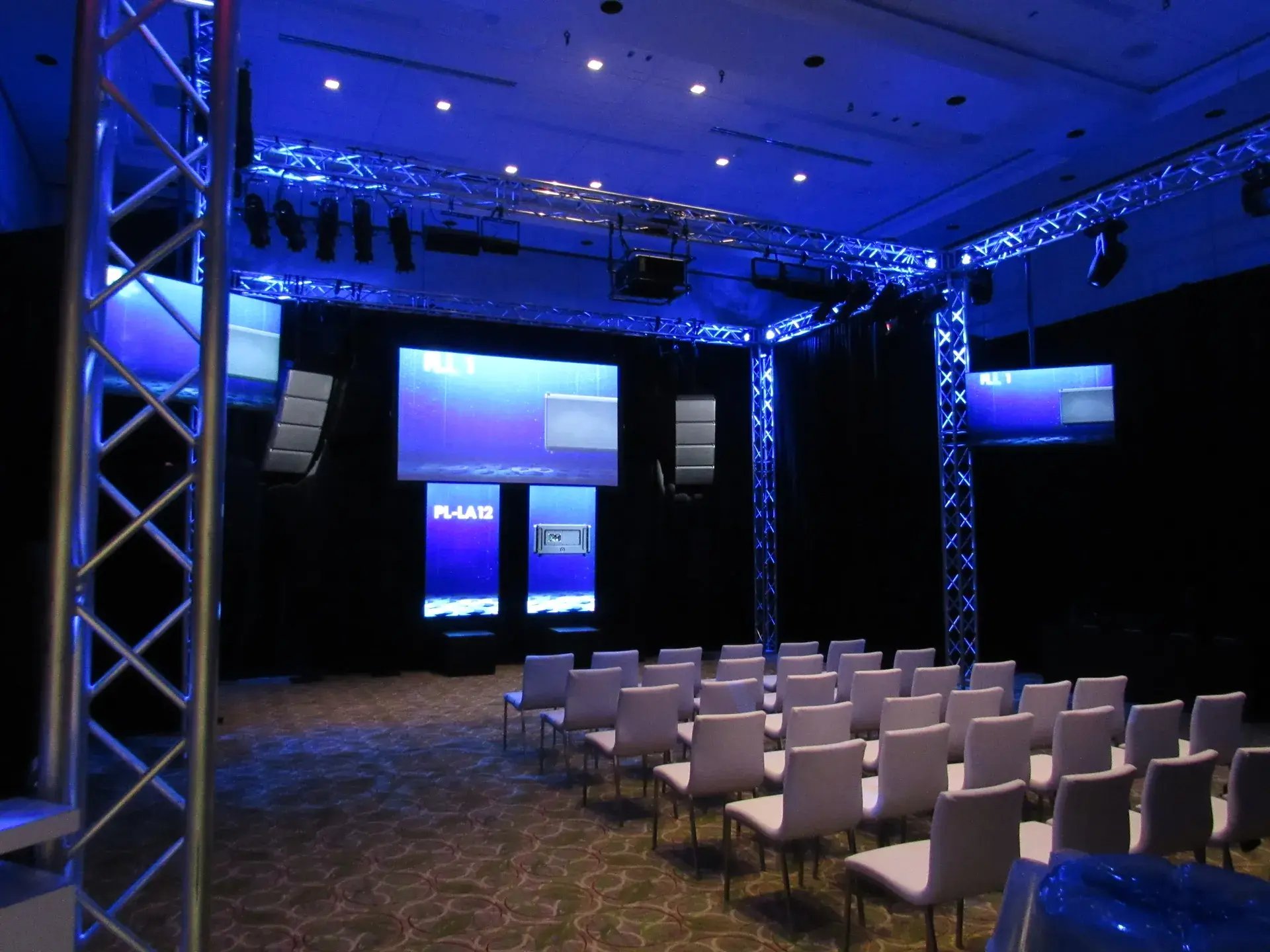 Presentation environment with stage truss, theatrical lighting, large-format displays and audience seating