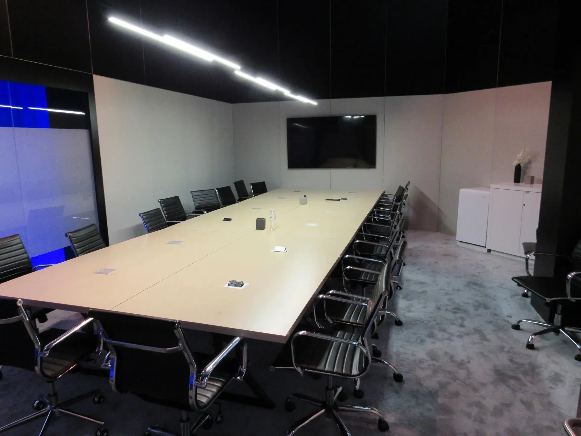 Private conference room with long meeting table, executive seating and integrated display