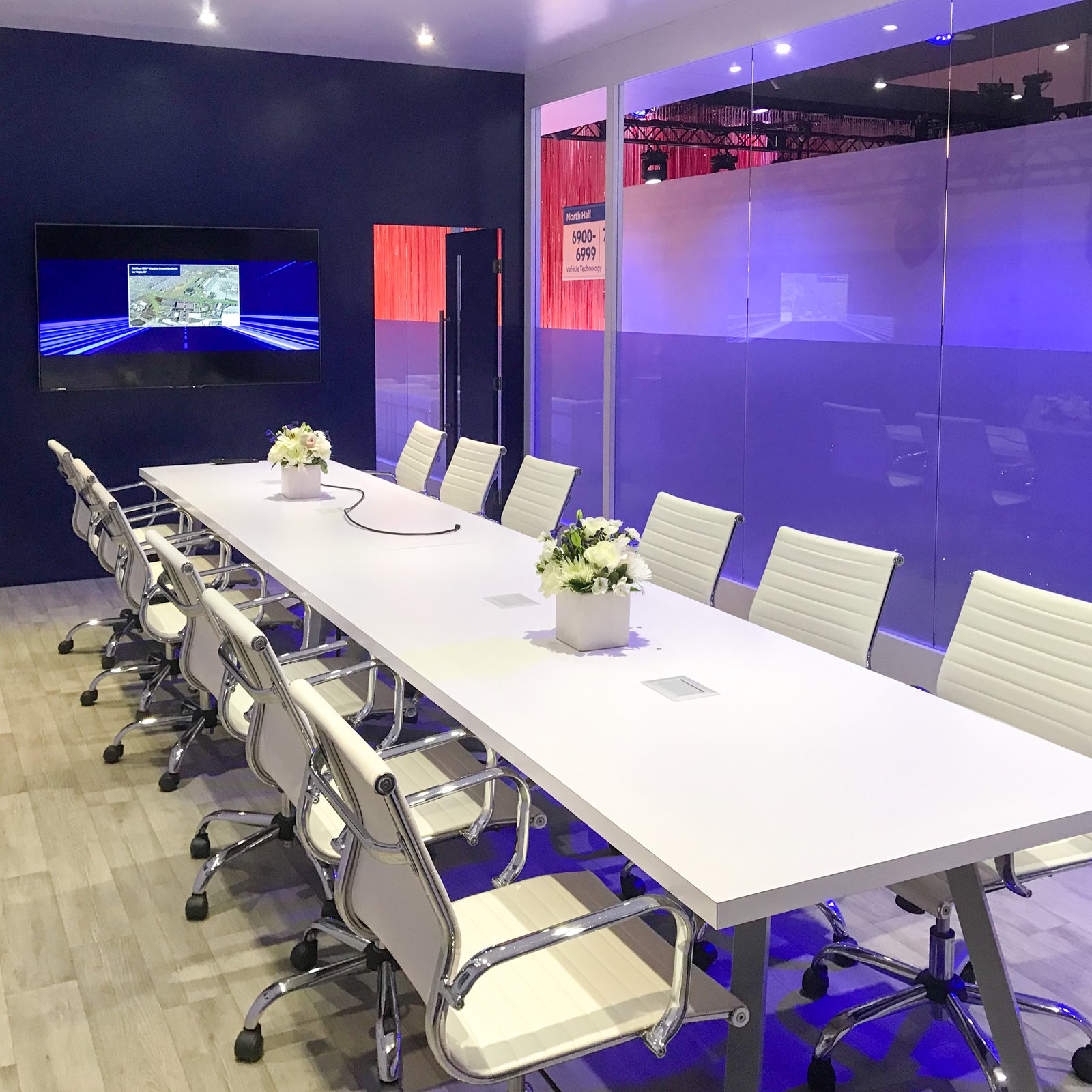 white chairs and white tables in a high tech conference room at mobileye's trade show booth