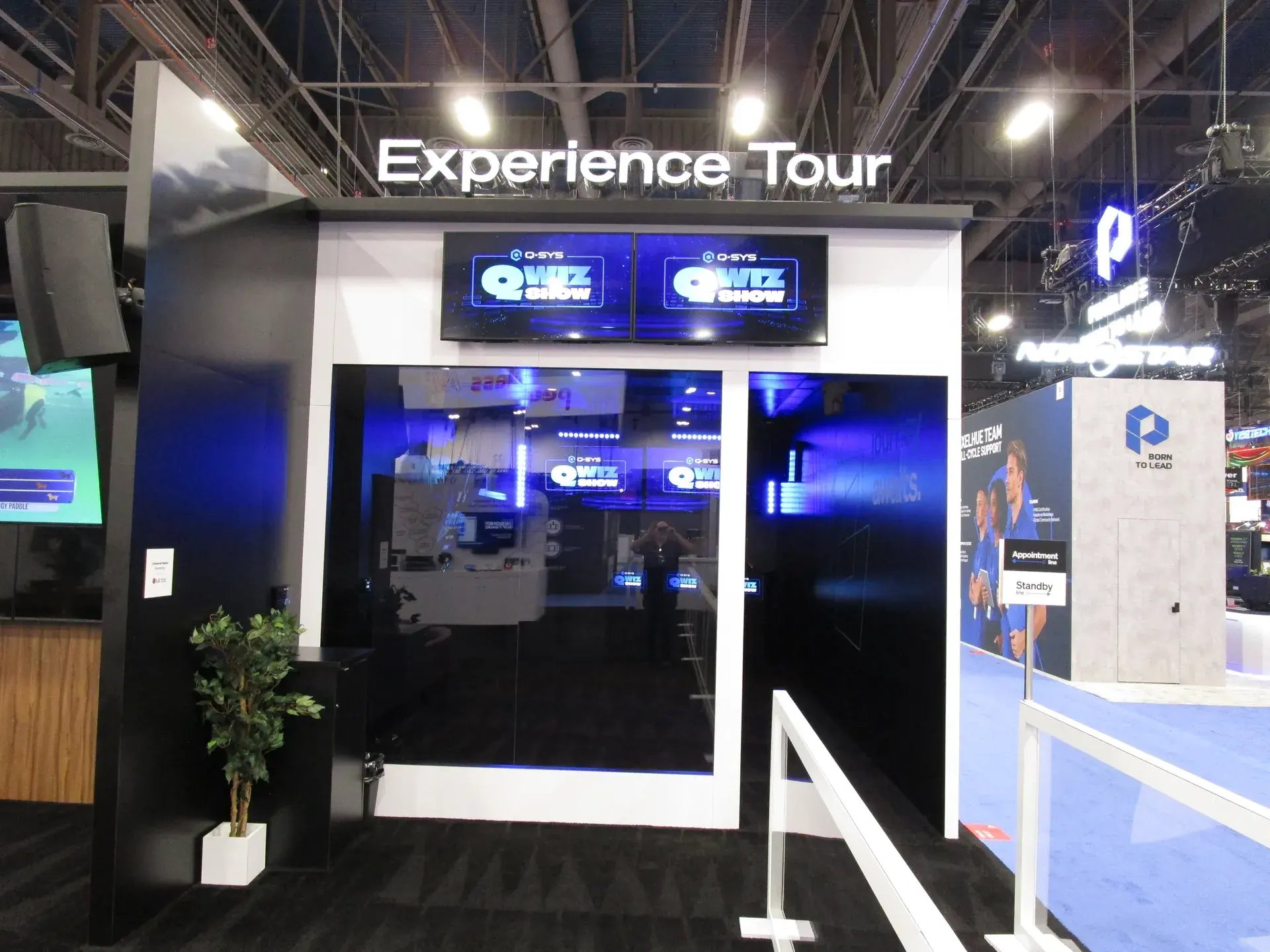 Experience Tour entrance to the Q-SYS exhibit with digital displays above the guided queue doorway