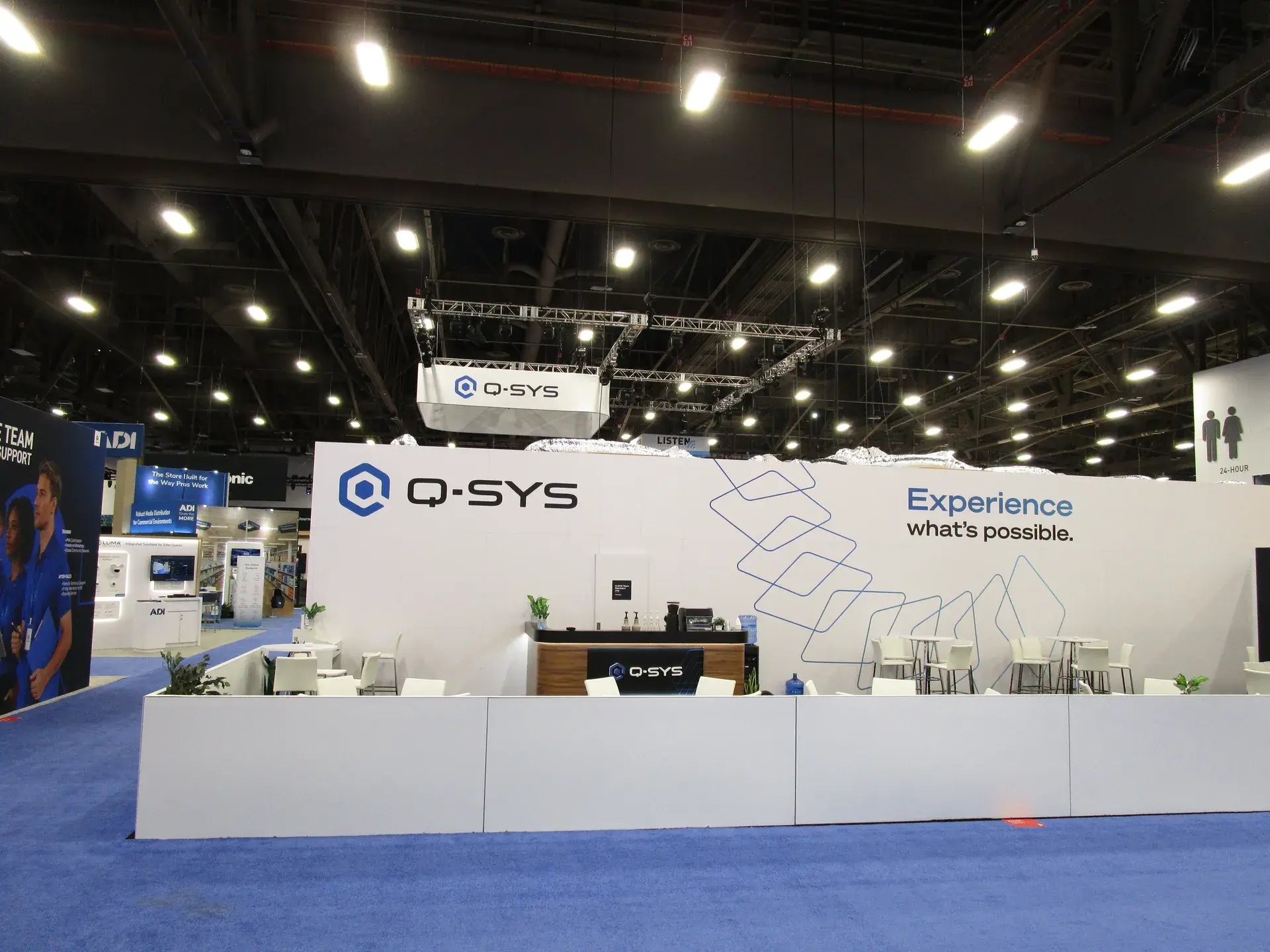Q-SYS exhibit exterior with large overhead hanging identification structure and branded architectural graphics
