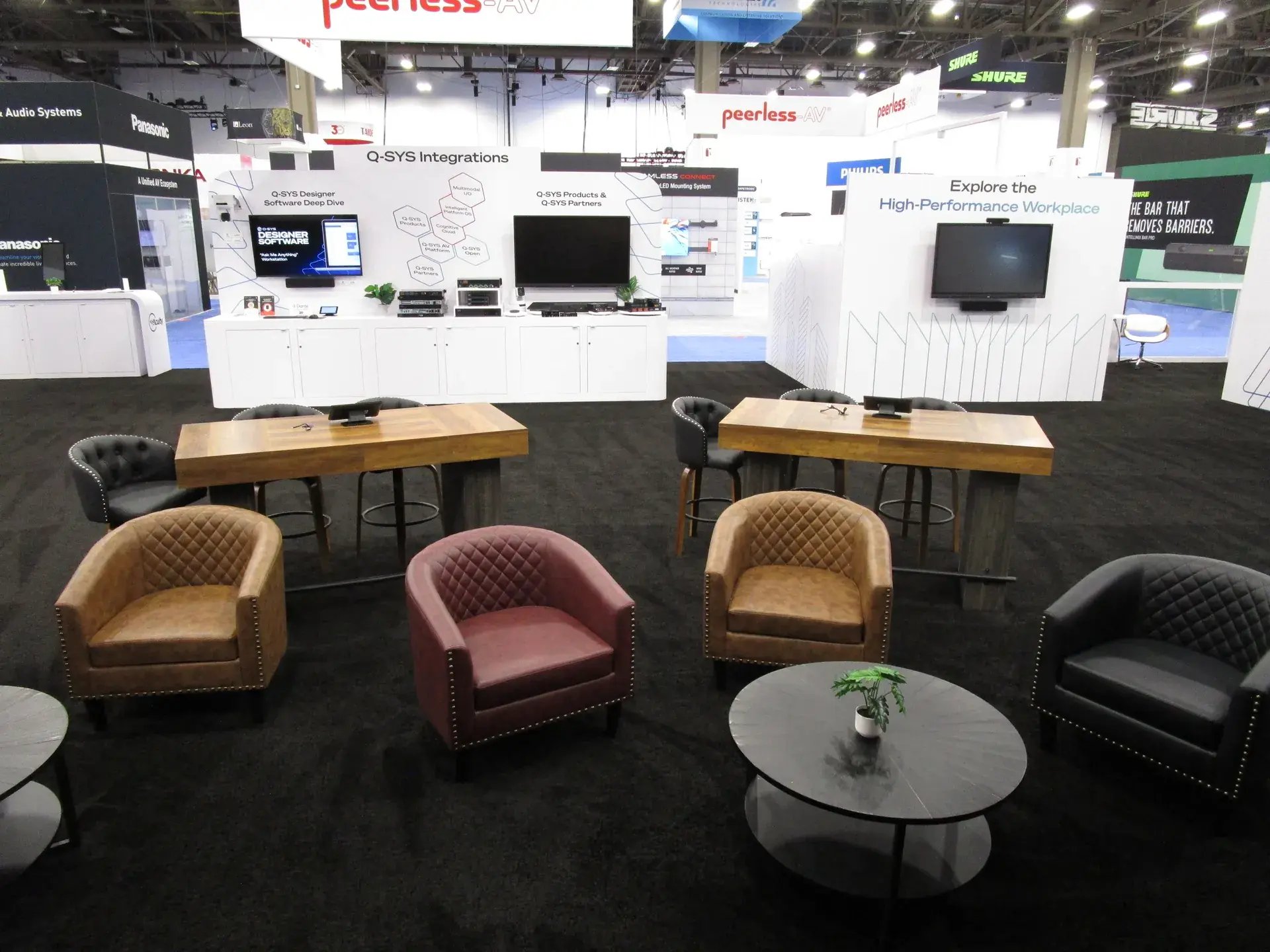 Hospitality lounge in the Q-SYS exhibit with leather club chairs and coffee tables