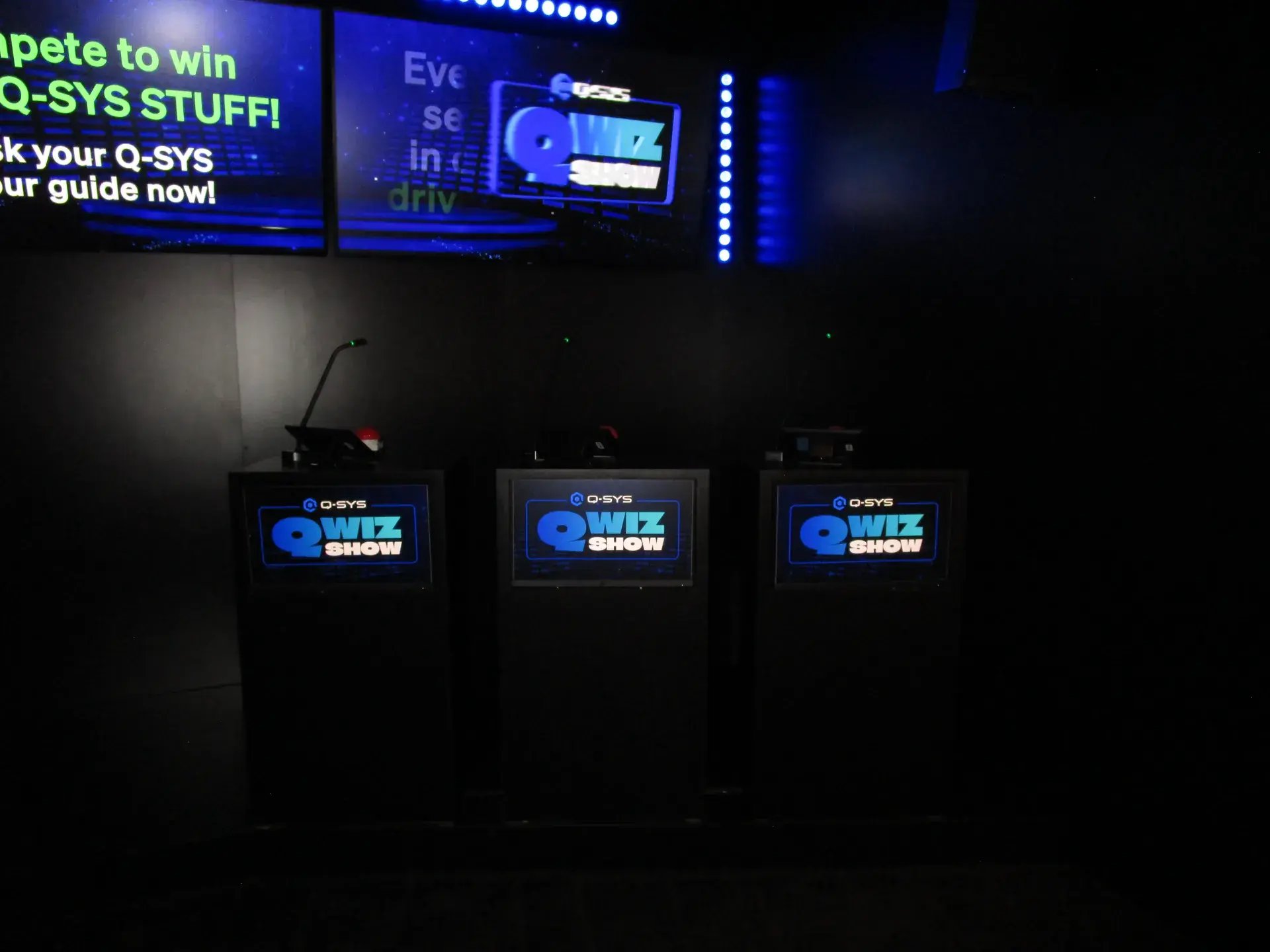 Qwizzing interactive quiz stations with custom podiums and integrated displays in a theatrically lit room