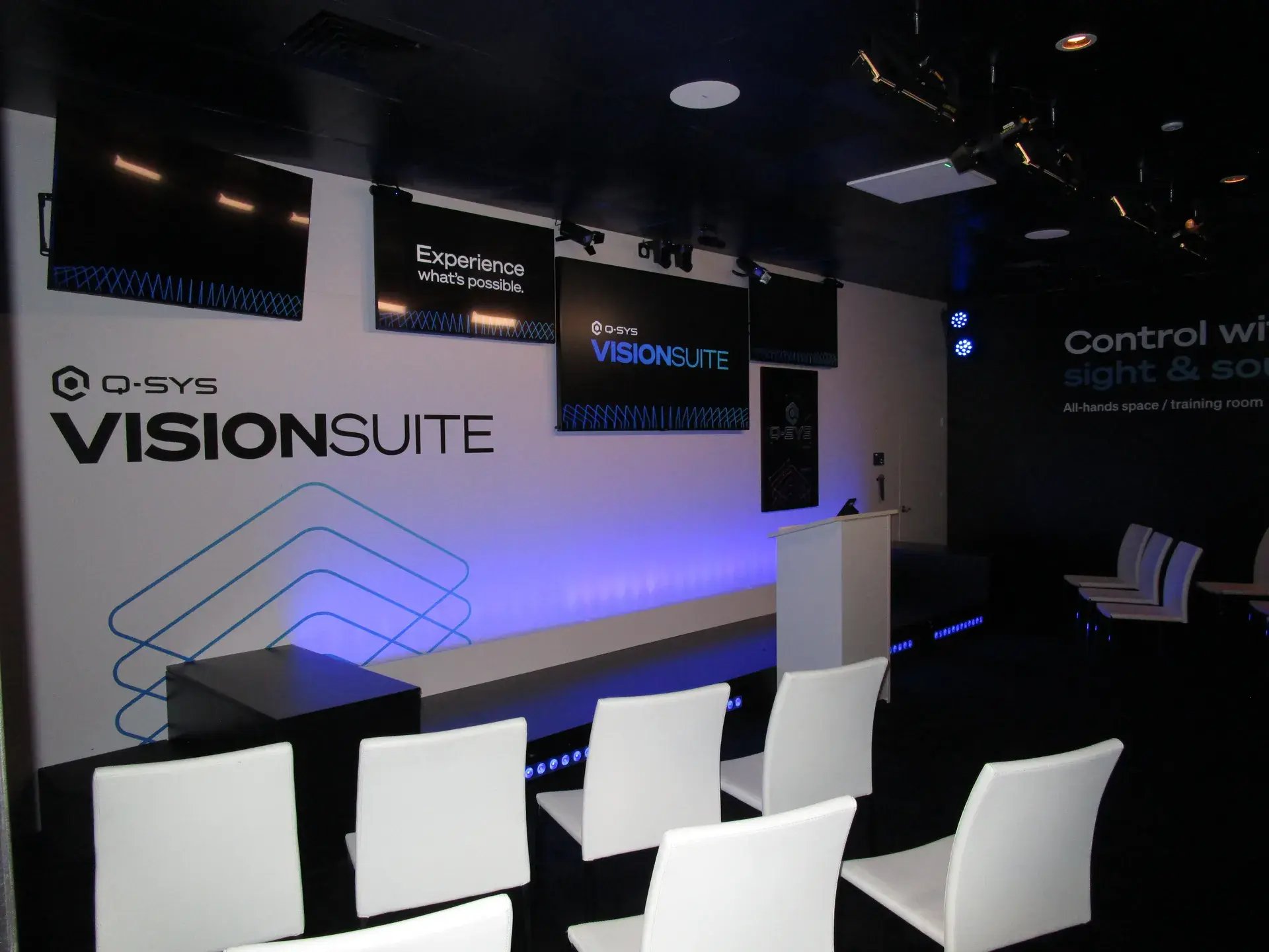 VisionSuite presentation theater with elevated stage, audience seating and large-format displays