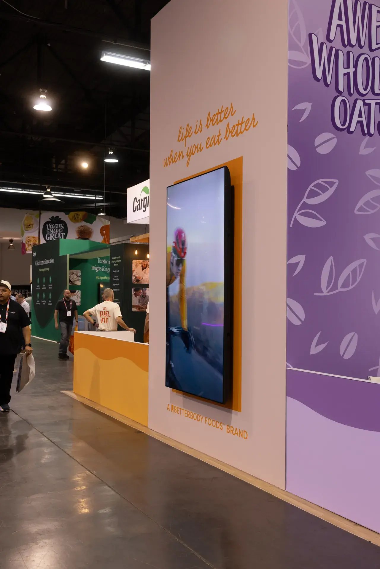Attendees engaging at the Oatsome wall and digital display