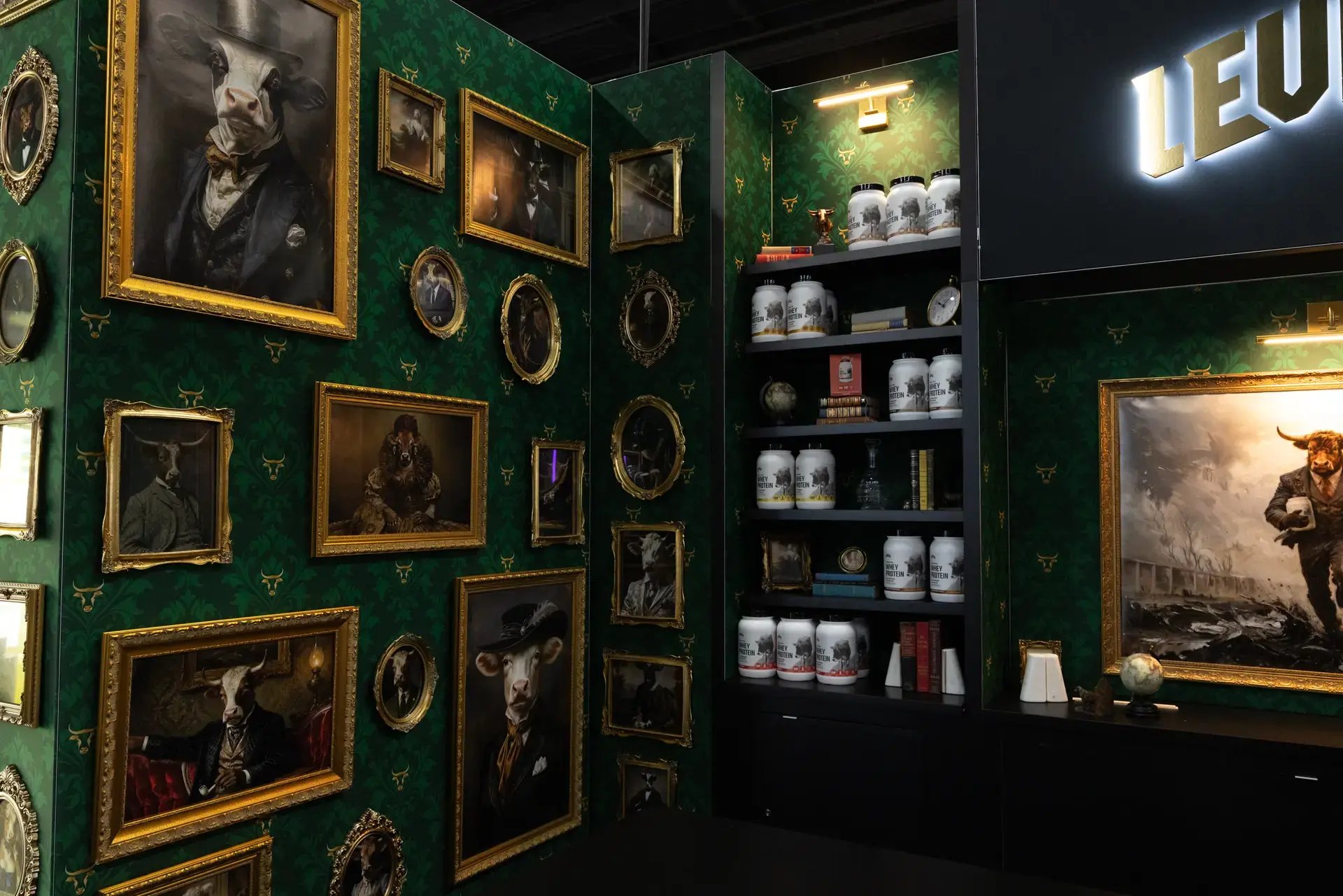 Emerald patterned side wall hung with gold-framed portraits beside black shelving stocked with LEVELS whey protein