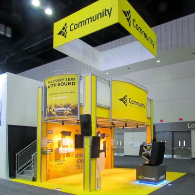 Bright yellow two-story Community trade show booth at Infocomm